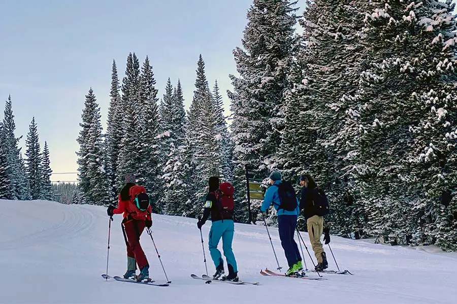 4 uphill skiers talking and climbing