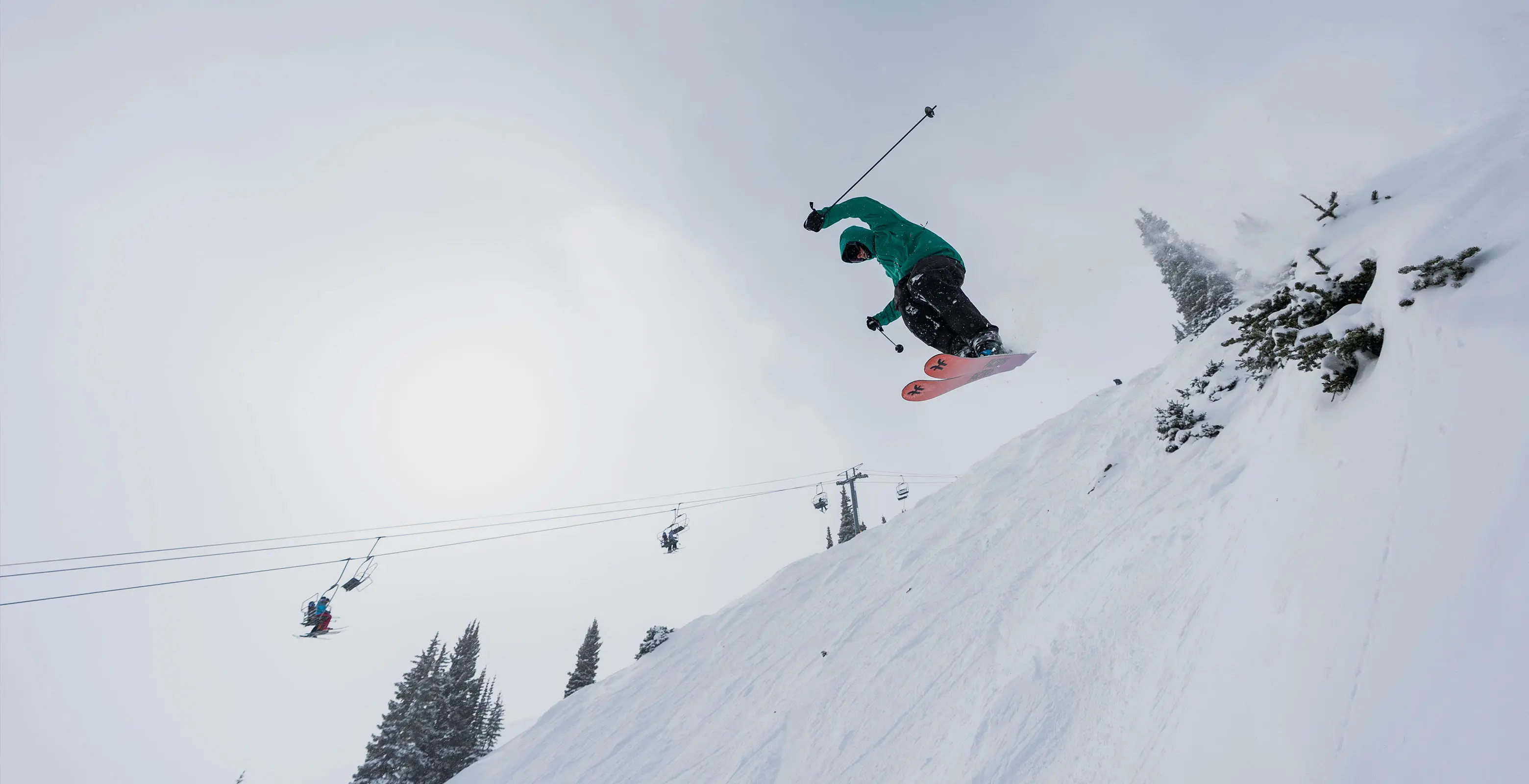 skier hitting a bush jump off of Sierra lift on a powder day